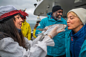 Tourist woman kiss the fish in the SH Vega cruise is an expedition cruise ship operated by Swan Hellenic, Iceland.