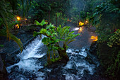 Heiße Quellen aus dem Arenal Vocano im Tabacón Grand Spa, Costa Rica. Ein Besucher genießt einen der warmen Bäche, die durch das Tabacon Hot Spring Resort and Spa in Costa Rica fließen