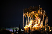 Seville, Spain, Apr 10 2017, Religious procession celebrating Holy Week in Seville with ornate canopy and candles.