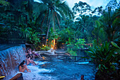 Heiße Quellen aus dem Arenal Vocano im Tabacón Grand Spa, Costa Rica. Ein Besucher genießt einen der warmen Bäche, die durch das Tabacon Hot Spring Resort and Spa in Costa Rica fließen