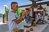 A man pours unhulled coffee beans into a huller machine during a tour of the coffee plantation in Colombia. The machine dehulls the beans, removing the parchment coating.