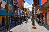 Tourists and colorfully-painted buildings along a street in the tourist town of Guatape, Colombia.