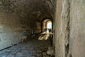 Tourists in the entrance tunnel of the Amphitheater of Pompeii in the ancient Roman ruins of Pompeii in Italy.