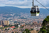 Eine Gondel des Medellin Metrocable Systems mit dem Stadtzentrum von Medellin, Kolumbien, im Hintergrund.