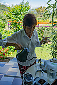 A woman pours water into a siphon coffee maker to brew coffee during a tour of a coffee farm in Colombia.