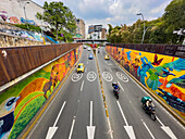 Der Verkehr fährt an bunten Wandmalereien in den Straßen von Cali, Kolumbien, vorbei.