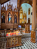 Votive candles burning at a side chapel in the Church of Our Lady of Carmen in Guatape, Colombia.
