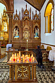 A worshipper at a side chapel in the Church of Our Lady of Carmen in Guatape, Colombia.