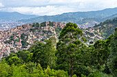 Die ärmeren Viertel in den Hügeln um Medellin, Kolumbien, mit einer Metrocable-Gondel auf der rechten Seite.