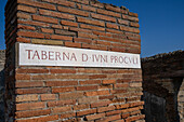 Sign for the ruins of the taberna or shop of Junius Proculus, I.4.15, in the ancient Roman ruins of Pompeii, Italy.