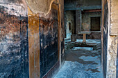The House of Fabius Amandius, Building I.7.2-3, in the ancient Roman ruins of Pompeii, Italy. A lead bucket embossed with zodiac signs stands next to the marble table.