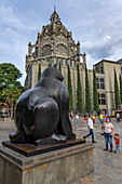 Cat, a sculpture by Fernando Botero in the Botero Plaza in Medellin, Colombia. Behind is the Palace of Culture.