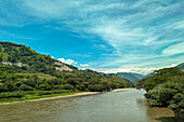 Der Cauca-Fluss bei Bolombolo, Kolumbien. Links ist die Autopista Conexion Pacifico 1 zu sehen. Kolumbien.