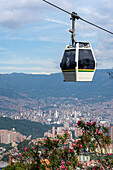 A gondola of the Medellin Metrocable system with downtown Medellin Colombia in the background.