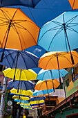 Colorful parasols provide shade on the Plazoleta de los Zócalos, a shopping street in Guatape, Colombia.