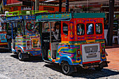 Eine Reihe farbenfroher Motochivas oder Mototaxis, touristische Verkehrsmittel in der Stadt Guatape, Kolumbien.