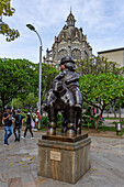 Man on Horseback, a sculpture by Fernando Botero in the Botero Plaza in Medellin, Colombia. Behind is the Palace of Culture.