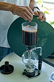 Stirring the coffee in a siphon coffee maker brewing coffee during a tour of a coffee farm in Colombia.
