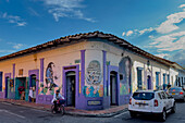 Colorful wall mural of flowers and people on a building with colonial-style architecture in Cali, Colombia.