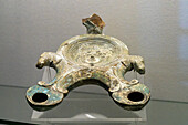 A large oil lamp with two nozzles in the Vesuvian Life Gallery, National Archaeological Museum of Naples, Naples, Italy. The lead-glazed terra cotta lamp is decorated with a Greek god and horse heads. From Pompeii, circa 1st Century A.D.