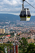 A gondola of the Medellin Metrocable system with downtown Medellin Colombia in the background.
