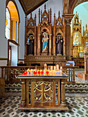 Votive candles burning at a side chapel in the Church of Our Lady of Carmen in Guatape, Colombia.