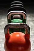 Bunte Kettlebells sind in einem Fitnessstudio aufgereiht, bereit für eine Trainingseinheit. Das Abendlicht schafft eine einladende Atmosphäre.