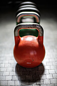Bunte Kettlebells sind in einem Fitnessstudio aufgereiht, bereit für eine Trainingseinheit. Das Abendlicht schafft eine einladende Atmosphäre.