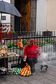 A woman selling incense on the street in front of the El Sagrario Church in Quito, Ecuador.