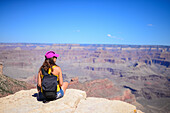 Sitting young woman enjoying the views of Grand Canyon, Arizona
