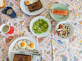Ein hausgemachter Brunch mit Spiegeleiern, Toast, frischer Avocado, Käsesalat und geräuchertem Lachs, ideal für einen faulen Morgen.