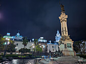 Nachtansicht des Unabhängigkeitsdenkmals auf der Plaza Grande in Quito, Ecuador, mit der Metropolitan-Kathedrale im Hintergrund.