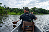Ein indigener Führer paddelt auf einer Tour im Napo Wildlife Center im Yasuni-Nationalpark, Ecuador, ein Kanu.