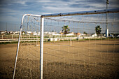 Ein Torpfosten steht auf einem unbefestigten Fußballplatz in Carrión de los Céspedes, Sevilla. Die ländliche Umgebung bietet eine ruhige, malerische Kulisse für das Spiel.
