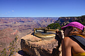 Junge Frau mit Suchgerät und Fernrohr am Rande des Grand Canyon