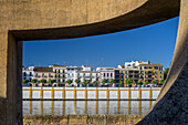 Calle Betis in Triana, Seville, shines through Chillida's Monument to Tolerance, highlighting vibrant architecture.