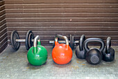 A diverse set of kettlebells rests neatly in a home gym, ready for strength training and fitness exercises to enhance workouts.