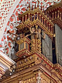 The ornately-carved pipe organ in the Basilica of Our Lady of Mercy in Quito, Ecuador. Decorated with angels blowing trumpets.