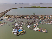 Aerial view of a destroyed fishing village with debris and boats after cyclone Sitrang, Potenga, Chittagong, Bangladesh.