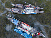 Aerial view of fishermen mending nets with moored boats in a peaceful harbor scene, Chittagong, Chittagong, Bangladesh.