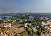 Luftaufnahme des Teuk Chhou Flusses, umgeben von üppigem Ackerland und einem friedlichen Dorf, Kampong Kraeng, Provinz Kampot, Kambodscha.