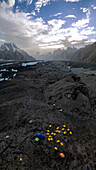 Aerial view of goro2 campsite with tents and majestic mountains under a dramatic sky, Skardu, Gilgit Baltistan, Pakistan.
