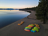 Luftaufnahme von Kyacks an einem ruhigen Strand am stillen See, umgeben von Bäumen bei Sonnenuntergang, Zephyr Cove, Nevada, Vereinigte Staaten.
