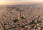 Aerial view of the iconic Basilica de la Sagrada Familia amidst a beautiful cityscape at sunset, Barcelona, Catalonia, Spain.
