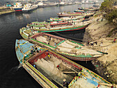 Dhaka, Bangladesch - 02. Februar 2025: Luftaufnahme des belebten Buriganga-Flusses mit traditionellen Booten und Zementindustrie, Darus Salam Thana, Dhaka, Bangladesch.