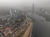 Luftaufnahme einer Stadtlandschaft mit Hochhäusern und dem Fluss Buriganga bei bedecktem Himmel, Lalbagh Thana, Dhaka, Bangladesch.