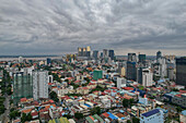 Luftaufnahme der pulsierenden Stadtsilhouette mit moderner Architektur und Hochhäusern unter einem bewölkten Himmel, Daun Penh District, Phnom Penh, Kambodscha.