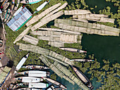 Aerial view of colorful fishing boats and nets on Kaptai Lake surrounded by vibrant foliage and serene shoreline, Rangamati, Chittagong, Bangladesh.