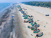Aerial view of colorful fishing boats on the coastline with golden sands and turquoise waters, Cox's Bazar, Bangladesh.