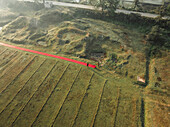Luftaufnahme einer Tuchfabrik mit Menschen, die Stoffe trocknen, umgeben von grünem Ackerland und ländlicher Landschaft, Paikar Char, Narsingdi, Dhaka, Bangladesch.